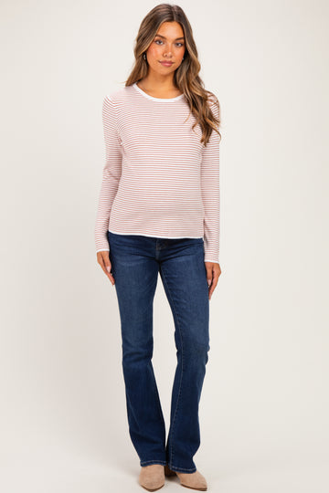 woman wearing a light pink and white striped long sleeve maternity top with a visible baby bump and blue jeans
