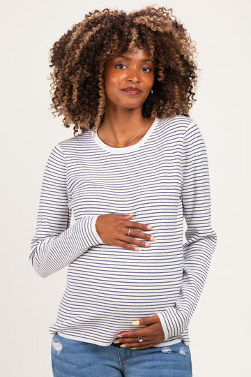 woman wearing a gray and white striped long sleeve maternity top and holding her baby bump