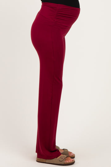 woman wearing burgundy maternity pants with side ruching, highlighting her baby bump