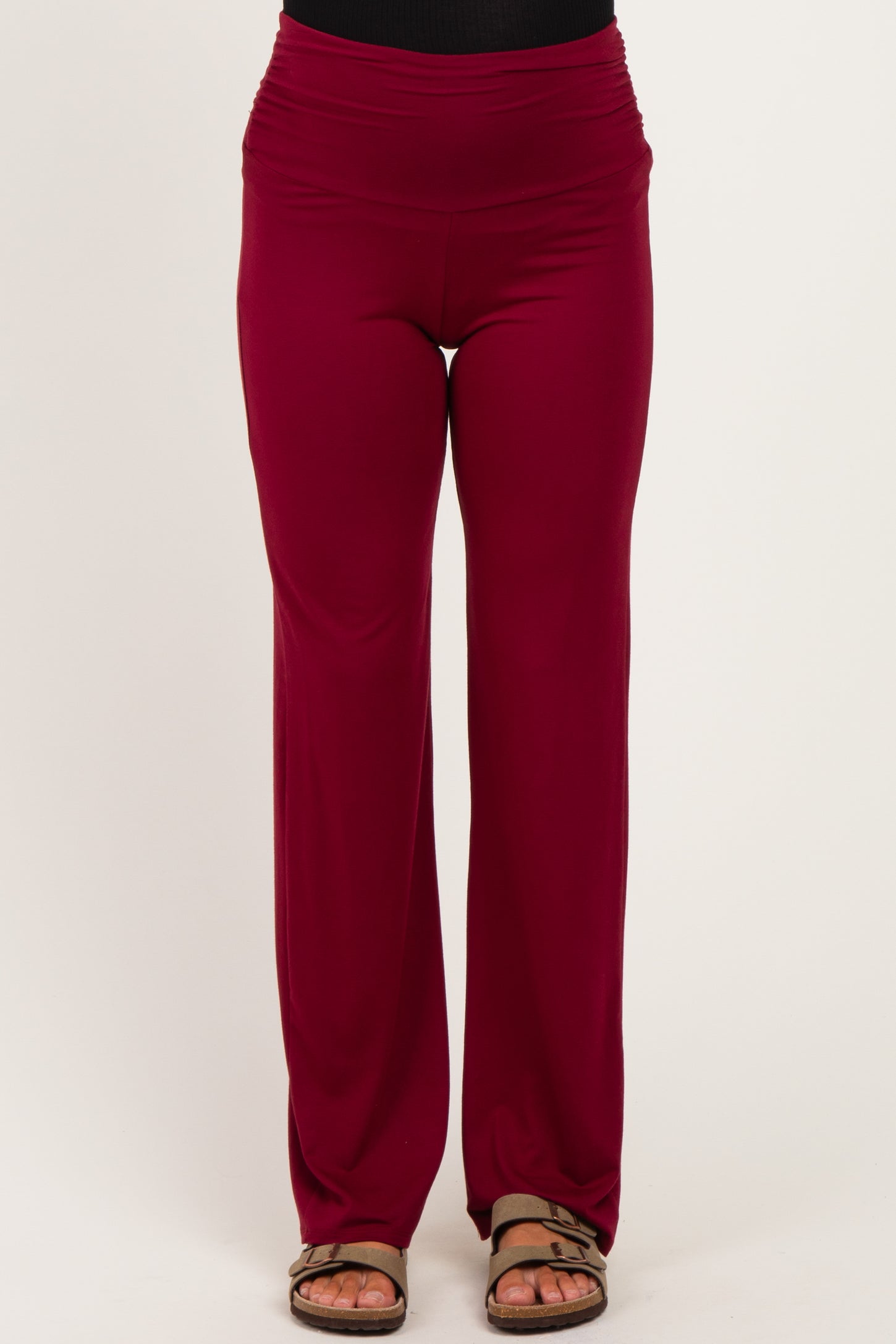 woman wearing burgundy maternity pants with a wide waistband and a relaxed fit