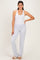 woman wearing a white sleeveless bodysuit and light gray lounge pants, posing with one hand on her hip