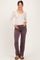woman wearing a beige long sleeve henley top and purple maternity pants, holding her baby bump
