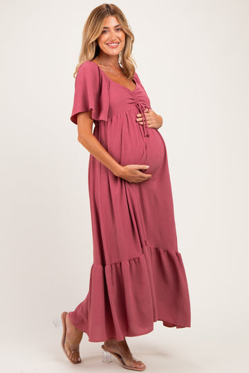 woman wearing a mauve maternity maxi dress with a tie front, holding her baby bump