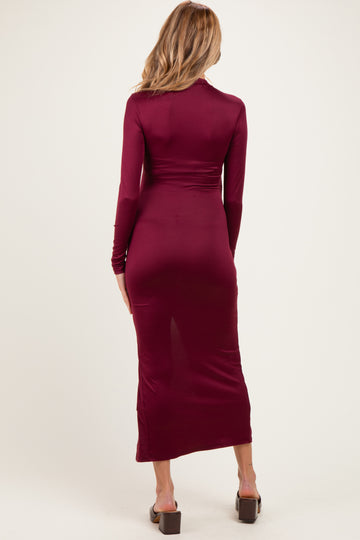 woman wearing a burgundy long sleeve maternity dress showing her baby bump from the back