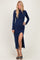 woman wearing a navy blue long sleeve maxi dress with a side slit and heels
