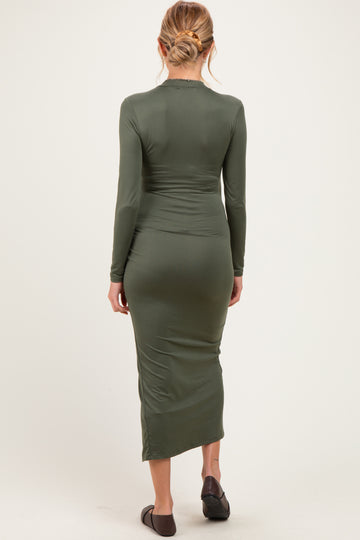 woman wearing a dark green long sleeve maternity dress with a fitted silhouette, showing a baby bump from the back