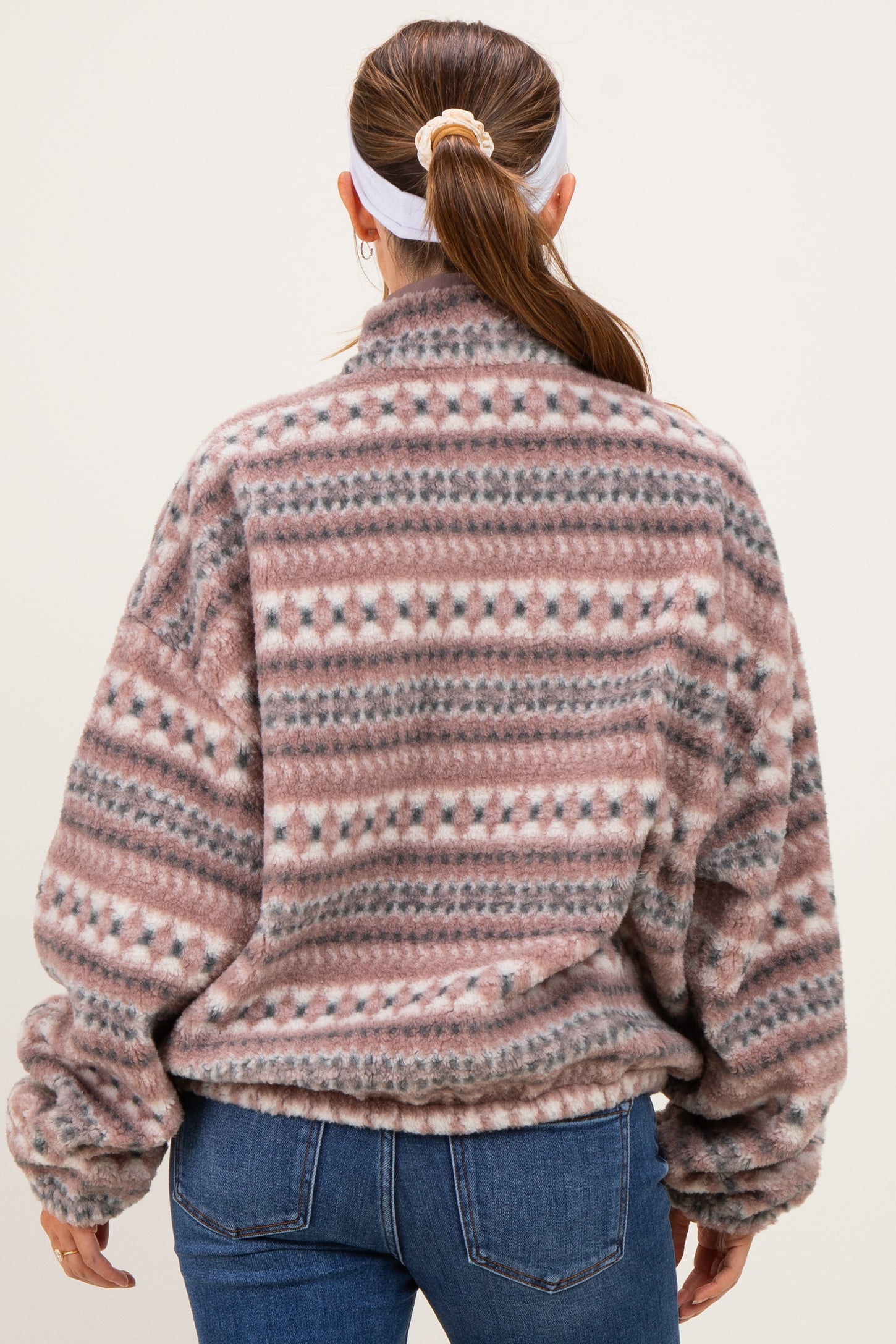 woman wearing a cozy pink and gray patterned maternity sweater with a soft, oversized fit, seen from the back