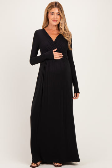 woman wearing a black long sleeve maternity dress and gently holding her baby bump