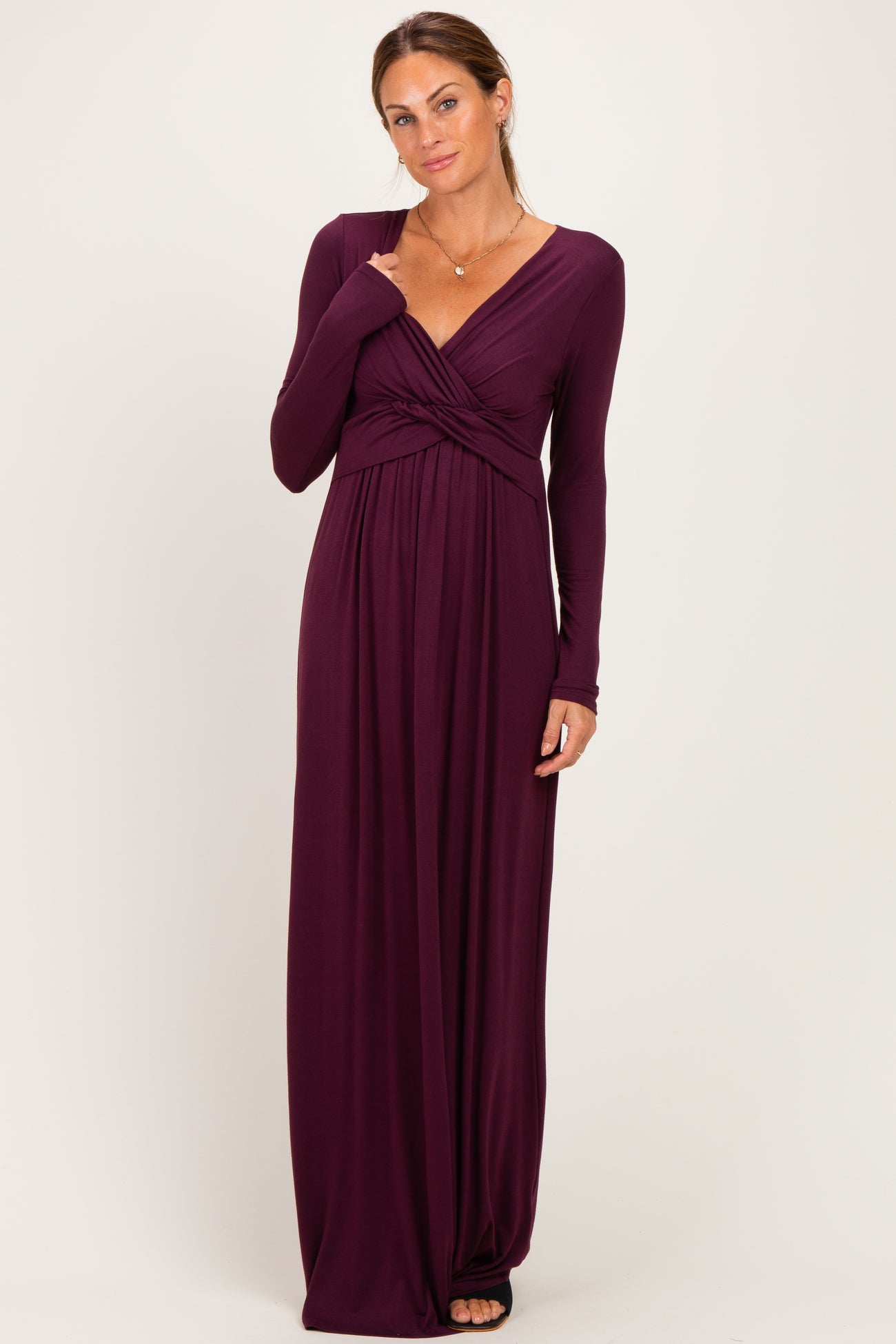 woman wearing a long sleeve deep plum maxi dress with a twisted front detail and a flattering silhouette