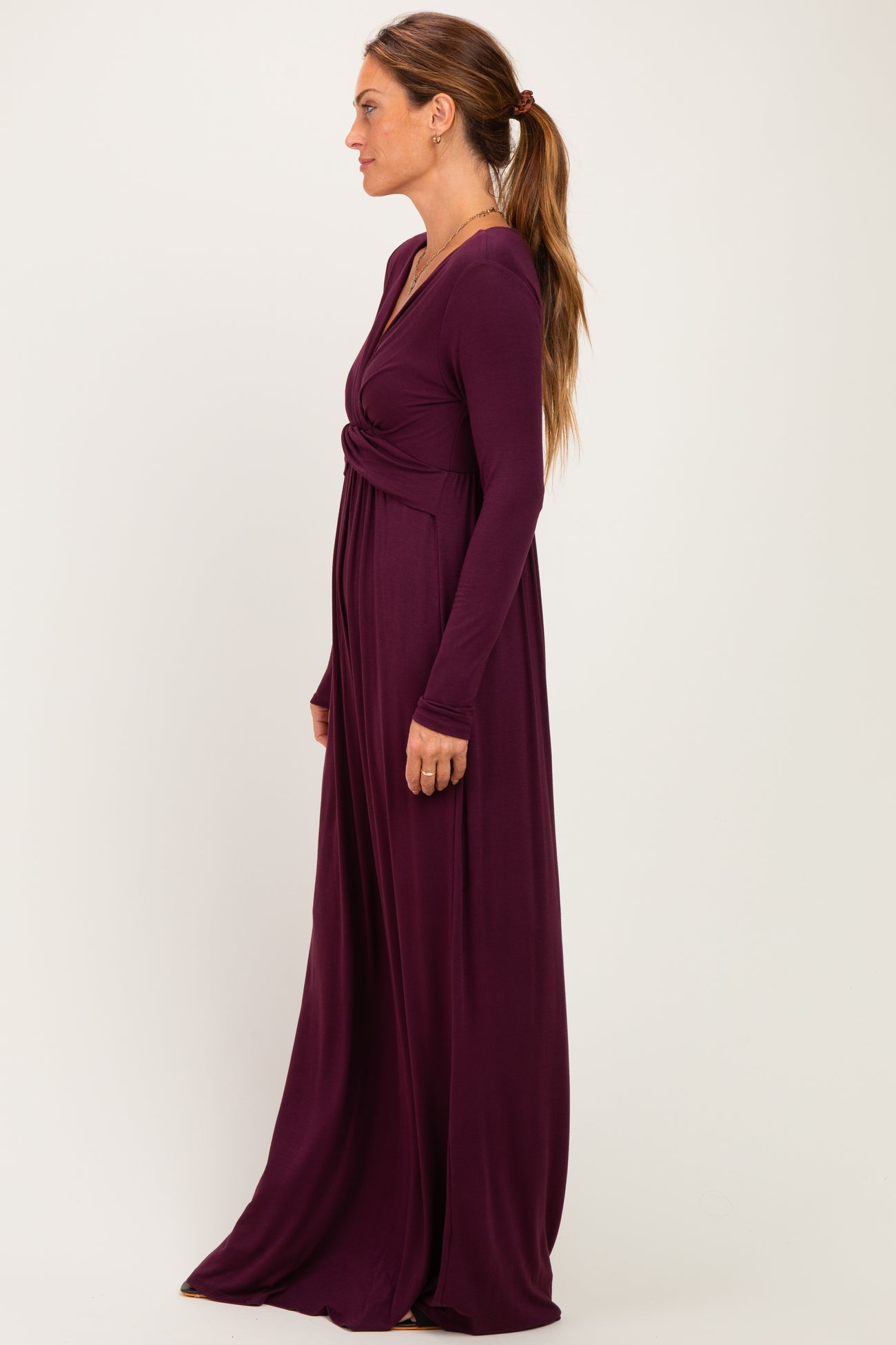 woman wearing a long sleeve purple maxi dress with a twist detail at the waist