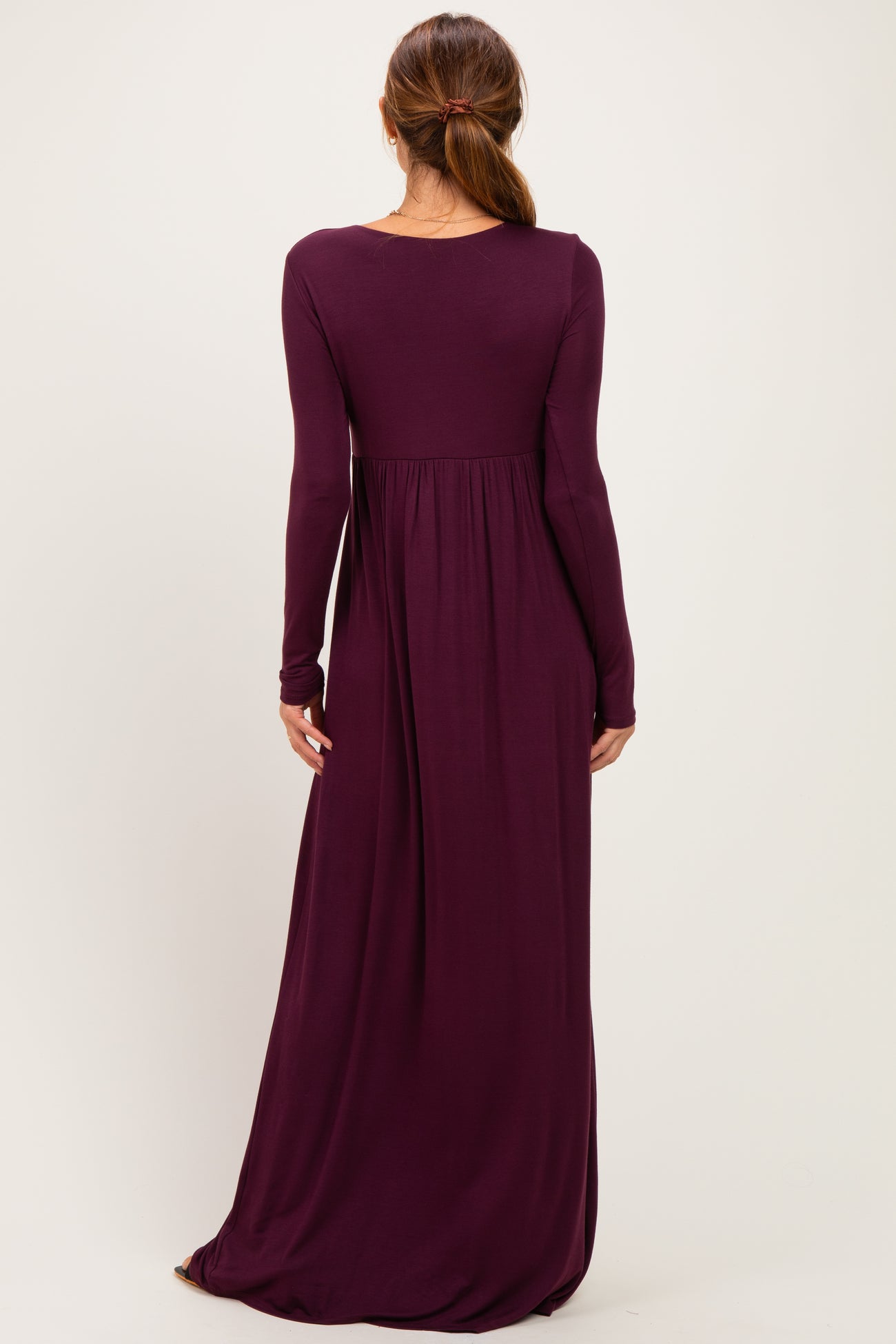woman wearing a long sleeve purple maxi dress with a flowy silhouette and a fitted bodice