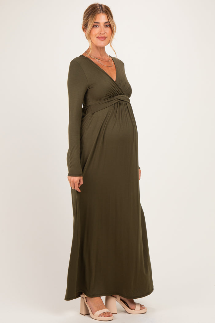 woman wearing a dark olive green long sleeve maternity dress with a twist detail and visible baby bump