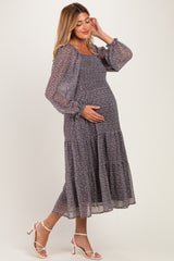 woman wearing a floral print long sleeve maternity dress with a tiered skirt, showing her baby bump