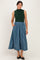woman wearing a sleeveless green knit top and a long blue and green striped skirt with pockets