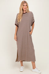 woman wearing a brown and white striped maxi dress with short sleeves and side pockets, standing in white sneakers