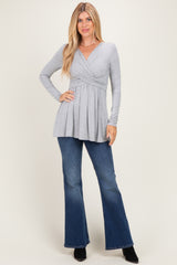 woman wearing a gray long sleeve top with a crossover neckline and flared jeans