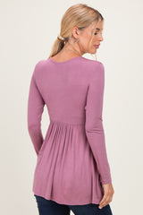 woman wearing a mauve long sleeve top with a gathered waist, viewed from the back