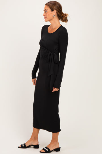 woman wearing a black long sleeve maxi dress with a front tie detail and ankle-length hem