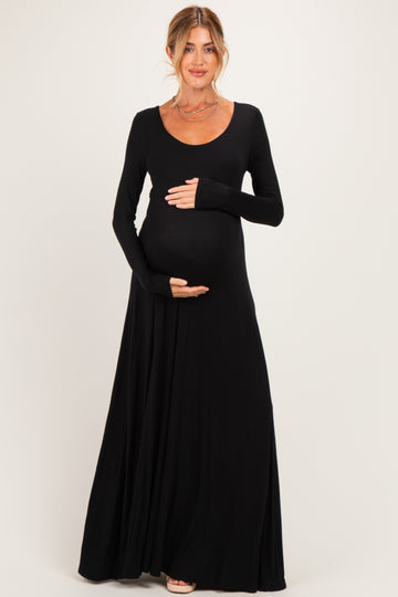 woman wearing a black long sleeve maternity dress with a scoop neckline and holding her baby bump