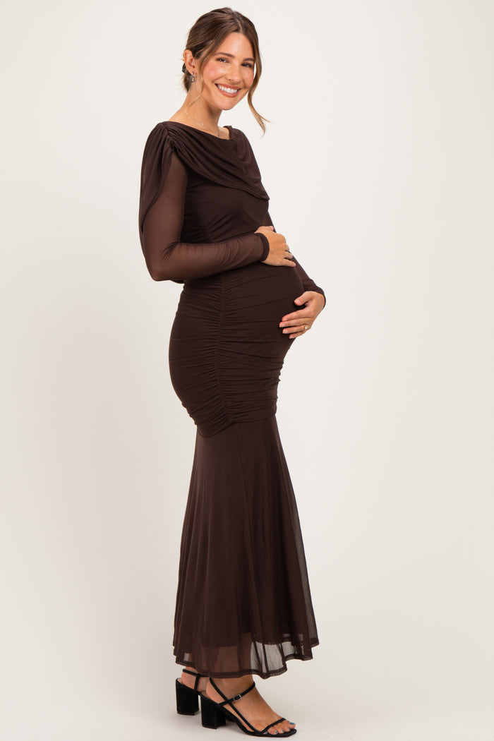 woman wearing a long sleeve brown maternity gown with ruching and a flared skirt, holding her baby bump
