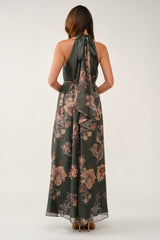 woman wearing a dark green floral maxi dress with a halter neck and flowing back detail