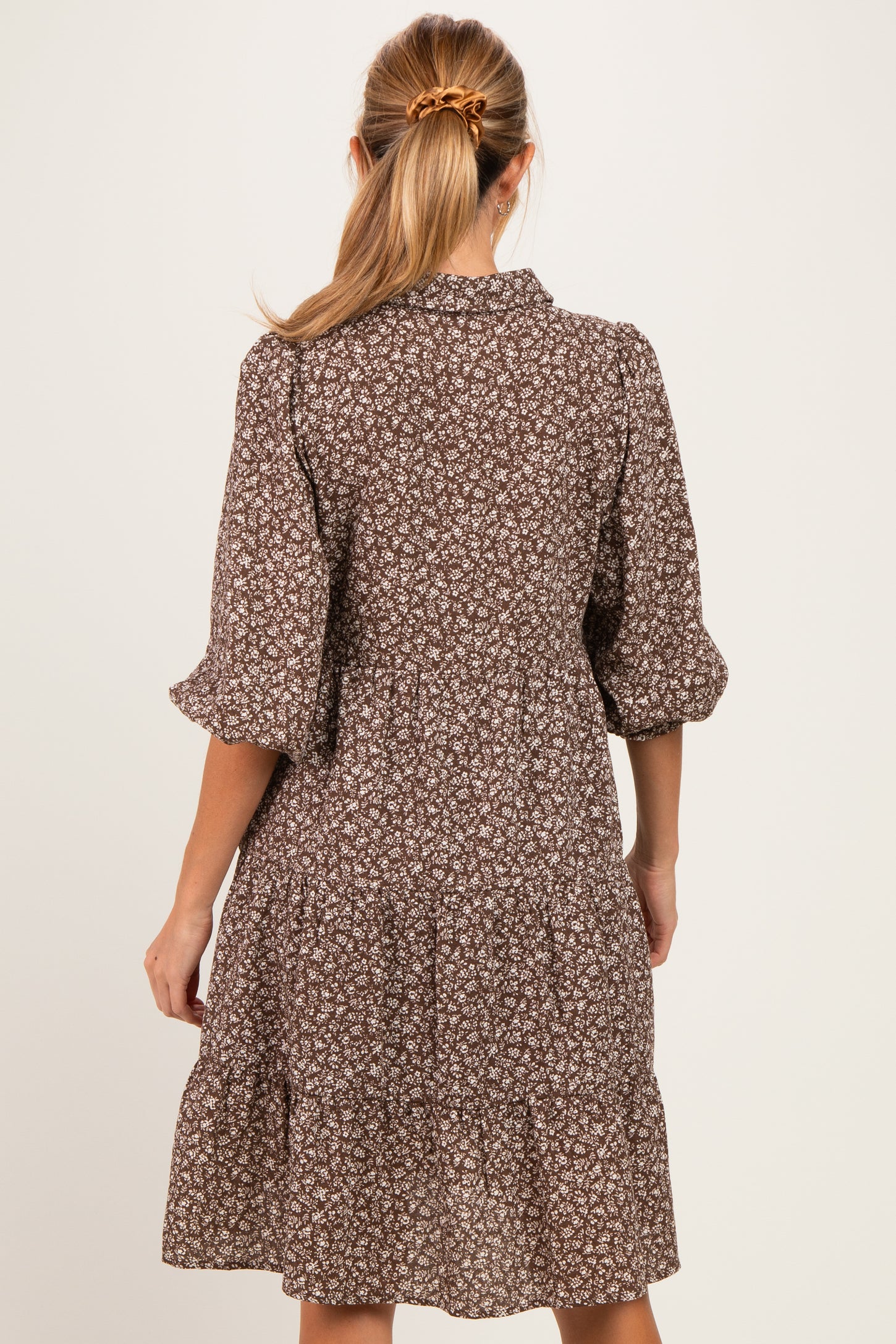 woman wearing a brown floral short sleeve maternity dress with tiered skirt and back button detail
