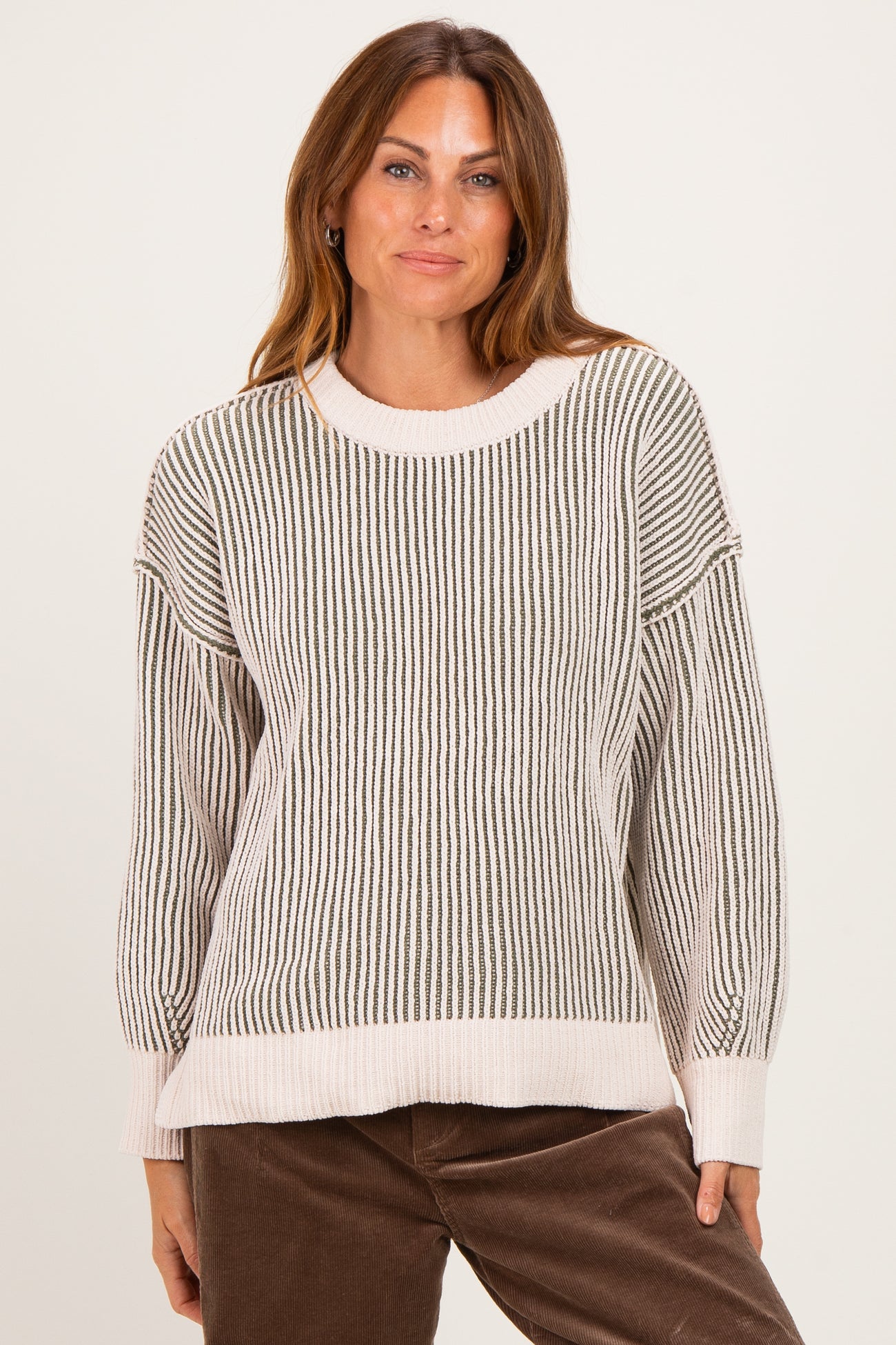 woman wearing a cream and gray striped oversized sweater with drop shoulders and a relaxed fit