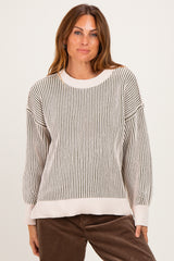 woman wearing a cream and gray striped oversized sweater with drop shoulders and a relaxed fit