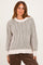 woman wearing a cream and gray striped oversized sweater with drop shoulders and a relaxed fit