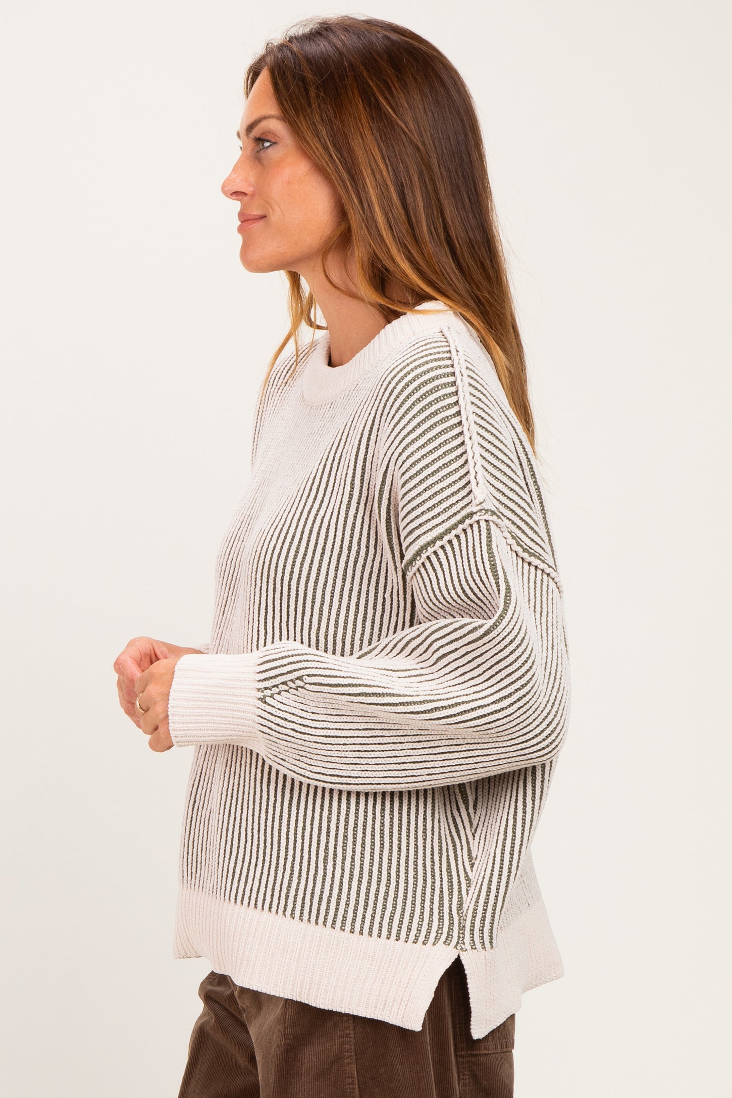 woman wearing a cream and gray striped knit sweater with a relaxed fit and dropped shoulders