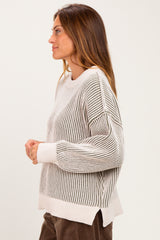 woman wearing a cream and gray striped knit sweater with a relaxed fit and dropped shoulders