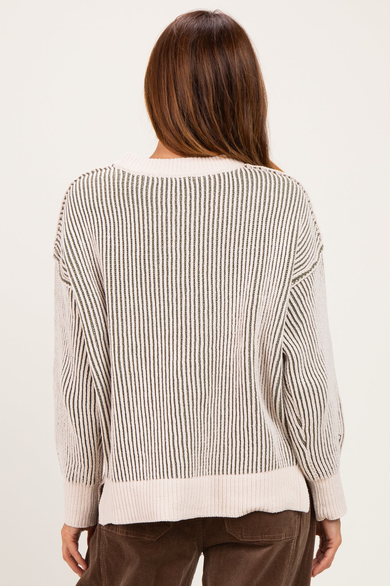 woman wearing a cream and beige striped oversized sweater, showing the back view