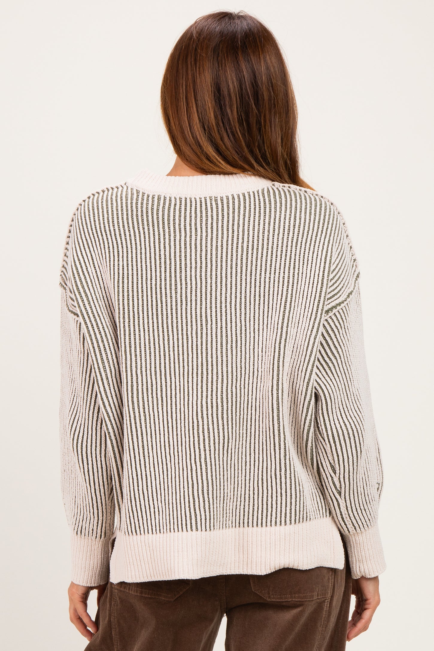 woman wearing a cream and beige striped oversized sweater, showing the back view