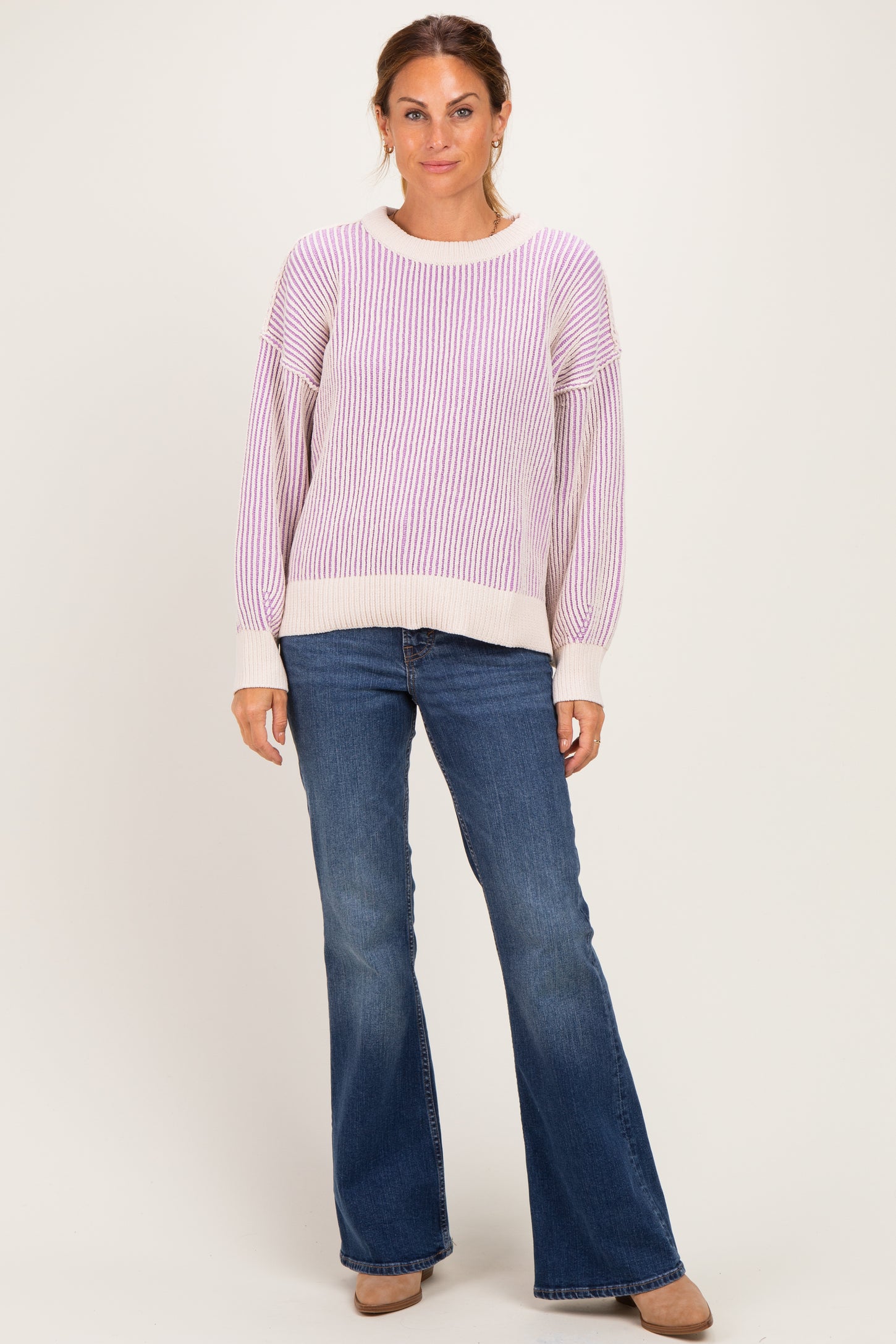 woman wearing a purple and white striped oversized sweater and blue flared jeans