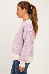 woman wearing a light purple and white striped sweater with ribbed texture and balloon sleeves, styled with blue jeans