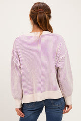 woman wearing a back view of a light beige and lilac striped oversized sweater with balloon sleeves and blue jeans