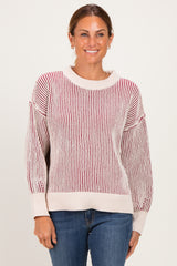 woman wearing a cream and red striped knit sweater with a relaxed fit and ribbed details, paired with blue jeans
