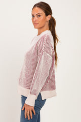 woman wearing a cream and burgundy striped knit sweater with a relaxed fit and long sleeves
