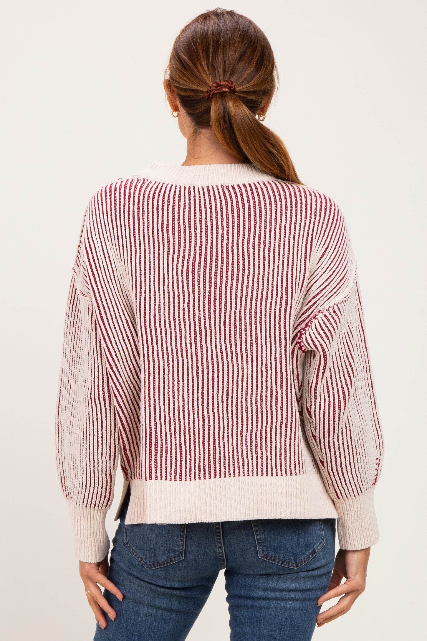 woman wearing a striped reddish beige sweater with balloon sleeves and back view, paired with blue jeans