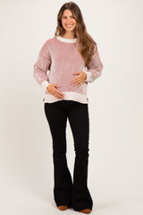 woman wearing a red and white striped maternity sweater and holding her baby bump, paired with black flared pants