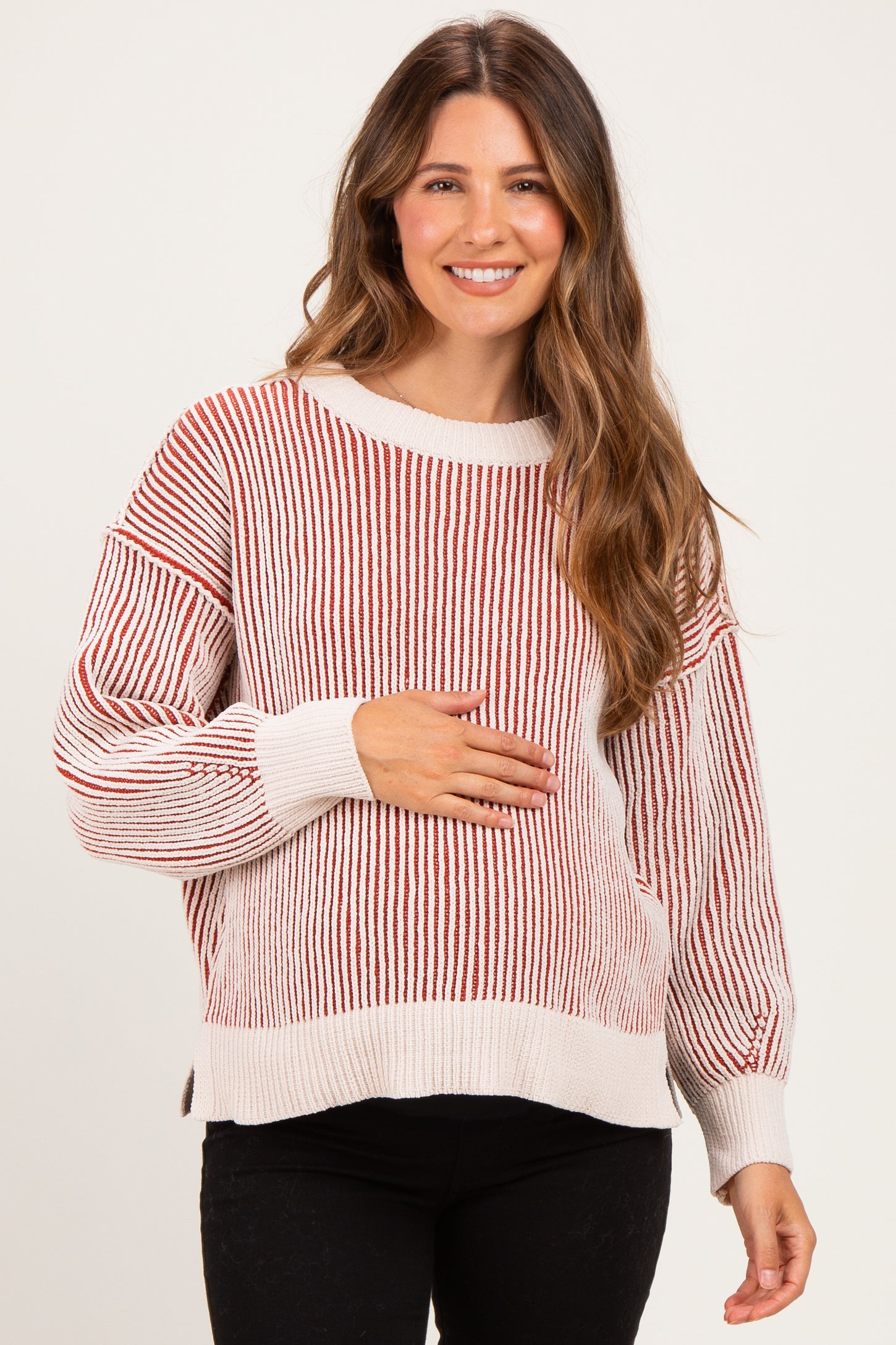 woman wearing a striped red and cream maternity sweater and holding her baby bump