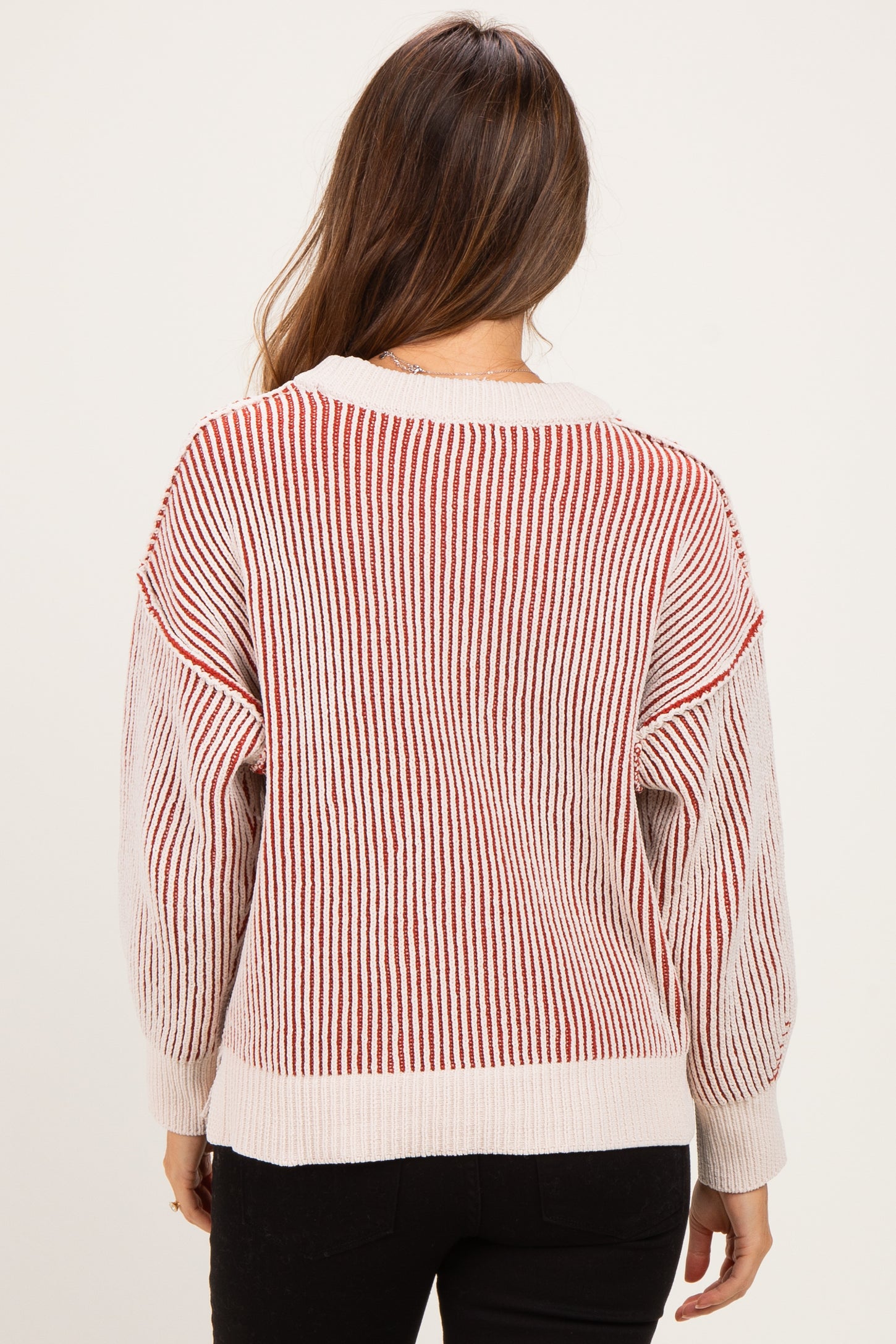 woman wearing a striped red and white oversized maternity sweater with balloon sleeves, seen from the back