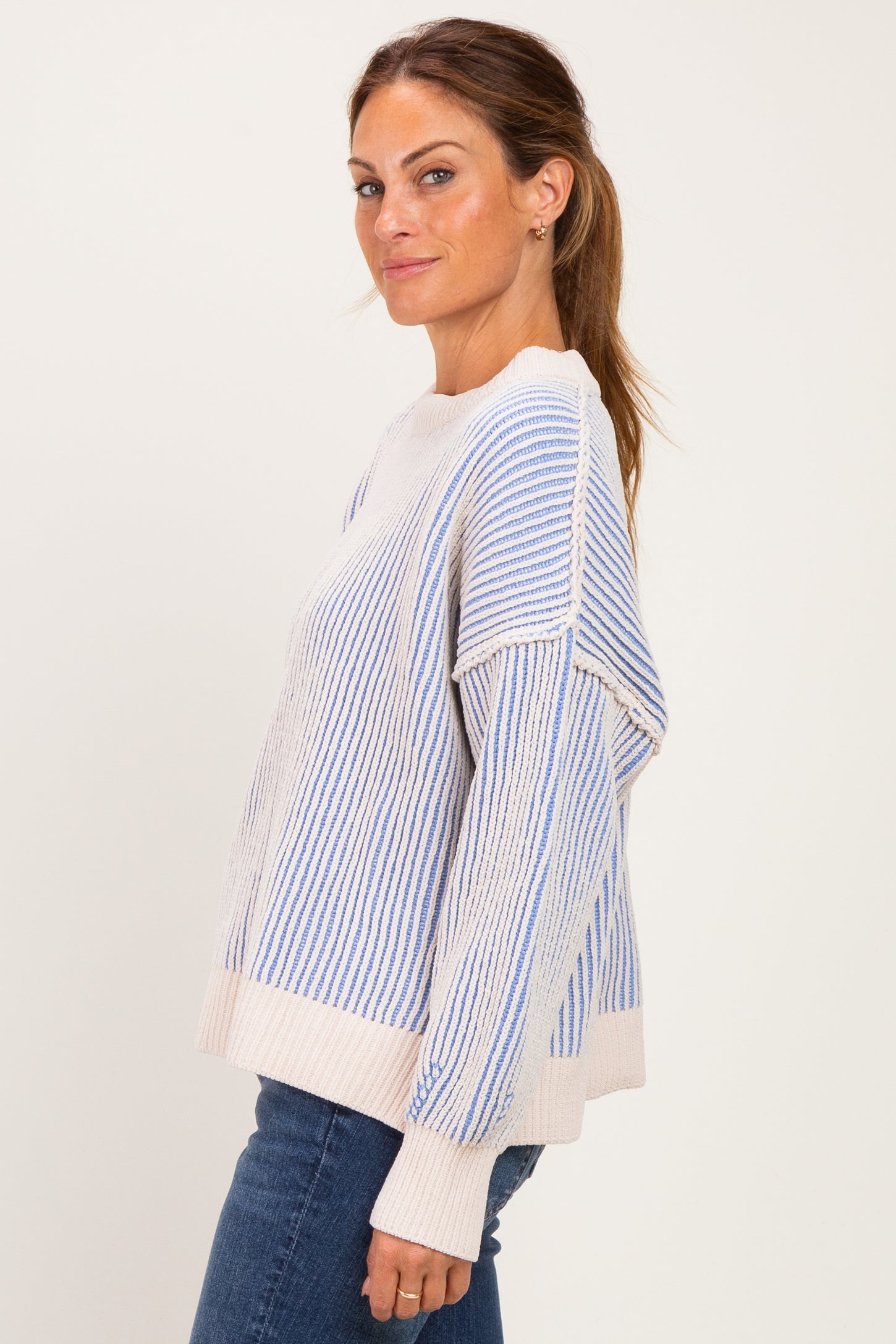 woman wearing a light blue and cream striped oversized sweater with dropped shoulders and a relaxed fit