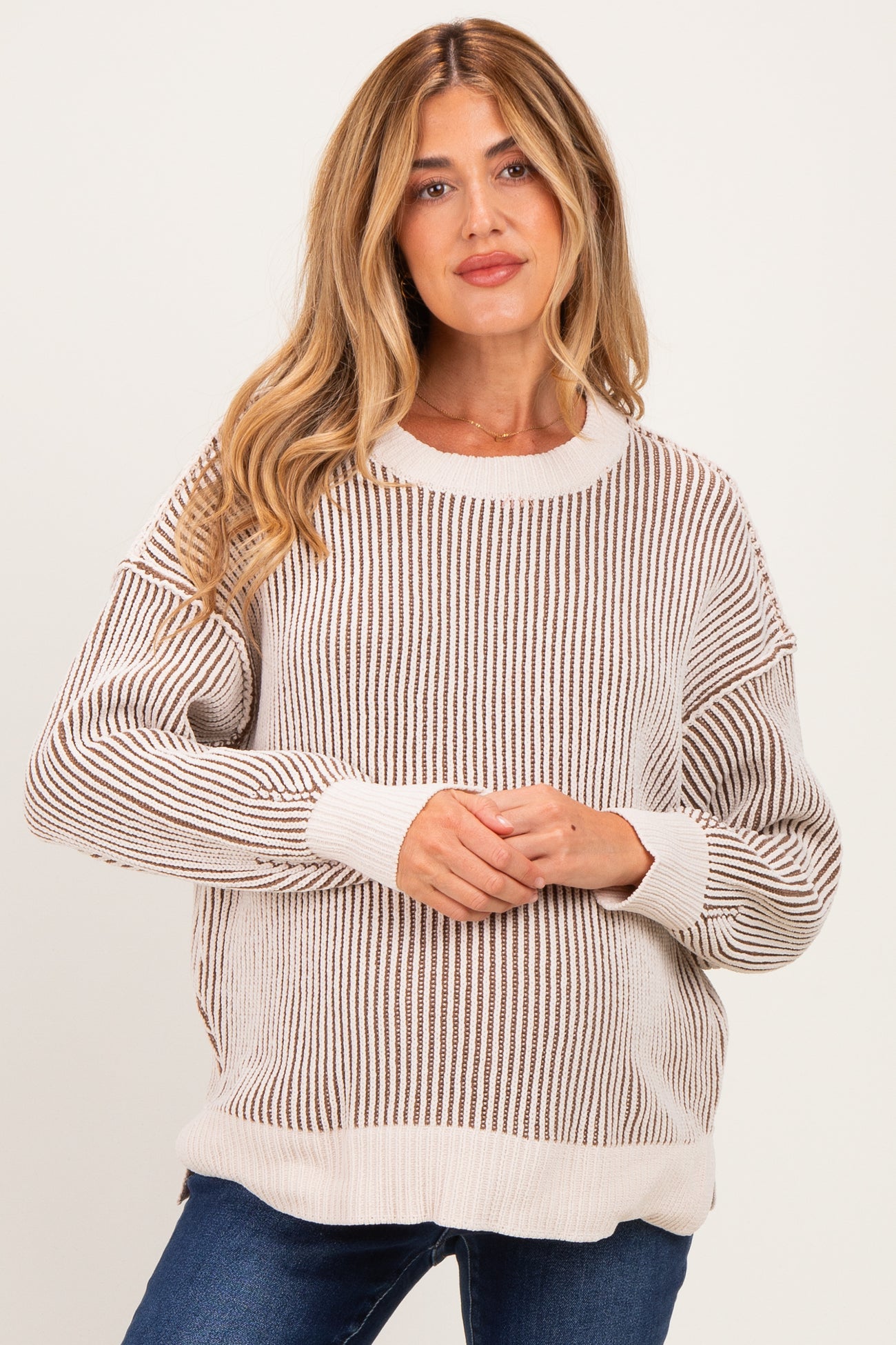 woman wearing a light beige striped knit maternity sweater with a relaxed fit and long sleeves