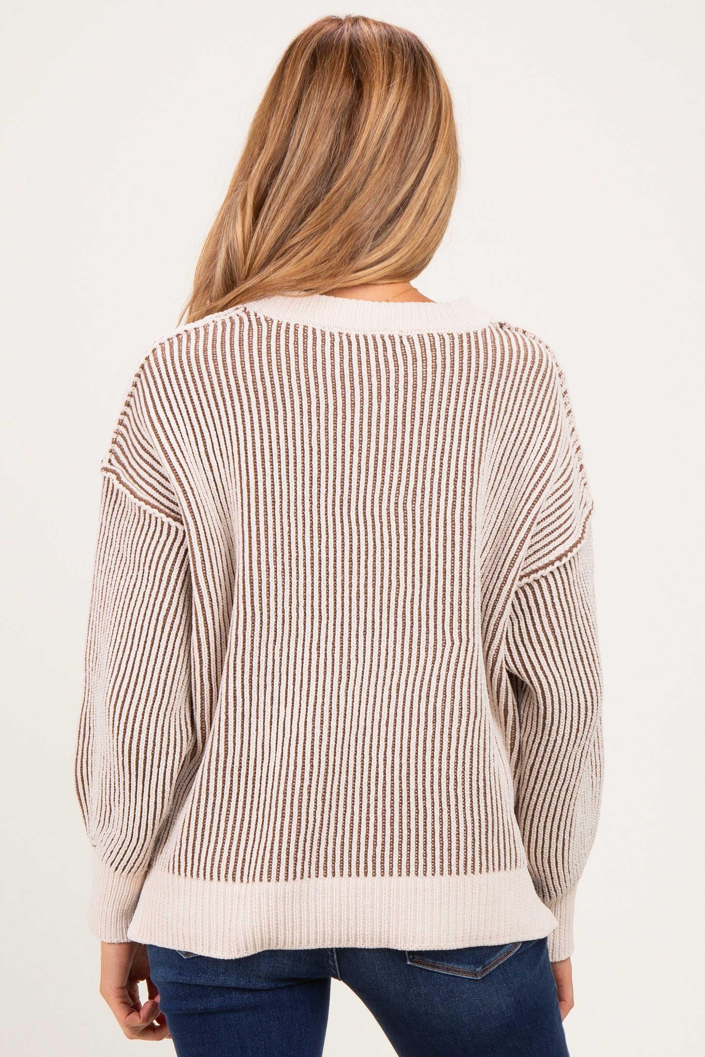 woman wearing a cream and brown striped maternity sweater, showing the back view with a relaxed fit