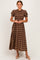 woman wearing a brown and tan plaid midi dress with puff sleeves and a cinched waist, standing in a neutral background