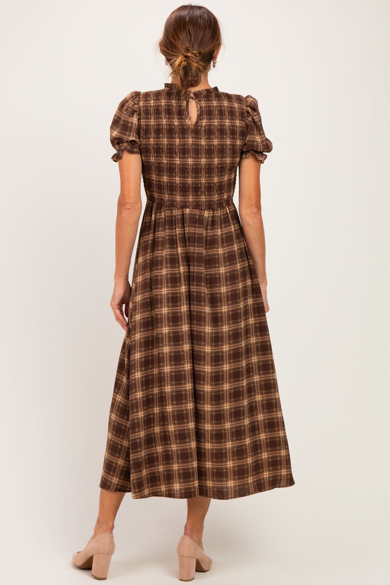 woman wearing a brown plaid maxi dress with puff sleeves and a keyhole back detail
