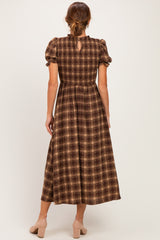 woman wearing a brown plaid maxi dress with puff sleeves and a keyhole back detail