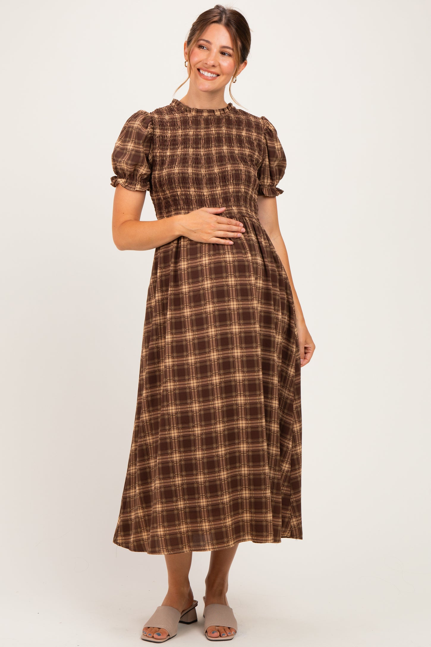 woman wearing a brown plaid maternity dress with smocked bodice and puff sleeves, showing her baby bump