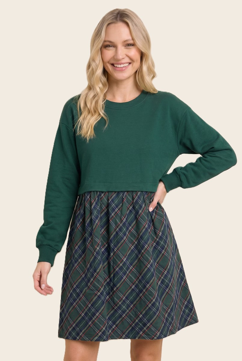 woman wearing a green cropped sweatshirt with a plaid skirt attached, smiling at the camera